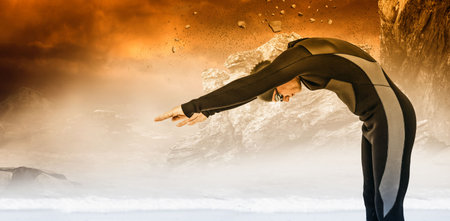 Side view of male swimmer diving against rock formations during sunsetの写真素材