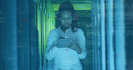 Female IT technician with red headset checking server status in data center, with tablet....
