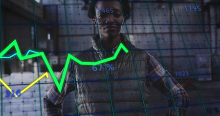 Standing data analyst wearing puffer vest scanning warehouse, overlaid with neon charts and grid. Technology, data, analytics, industrial, workspace, futuristic, businessの写真素材