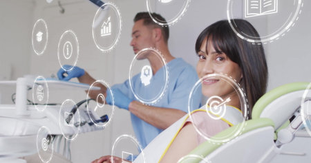 Smiling female patient reclining on chair in clinic room, with tray and digital icons, copy space. Dental, healthcare, medical, consultation, technology, oral hygiene, professionalの写真素材