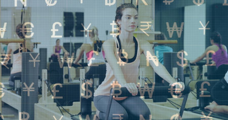 Gripping foot bar, woman wearing tank top and leggings performing Pilates in studio, with mirrors....