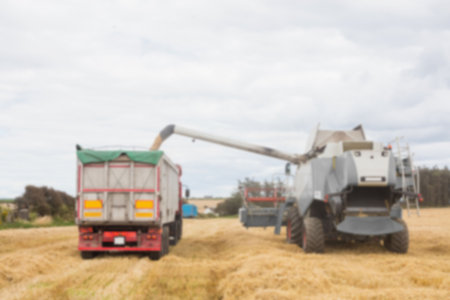 Defocused image of combine harvester on field against cloudy sky
