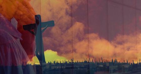 Clasping man holding wooden cross in window reflection with grass horizon and skyline, copy space....