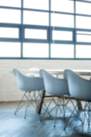 Empty chairs by table on floor against windowsの写真素材