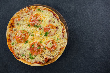 Overhead view of fresh pizza served on black tableの写真素材