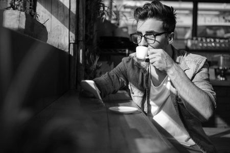 Man using mobile phone while having cup of tea in cafÃÂ©の写真素材