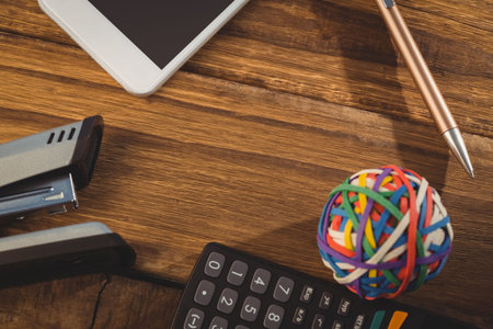 Overhead view of rubber band ball with office supply on wooden table