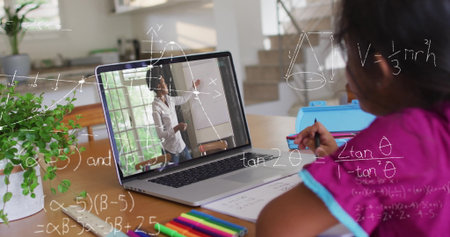 Student in fuchsia shirt writing geometry notes in notebook at home desk with laptop, copy space....
