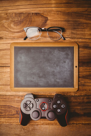 Chalkboard is lying on warm wood planks, in flat illustration with eyeglasses and game controller. Sketch, workspace, modern, technology, relaxation, cozy, minimalistの写真素材