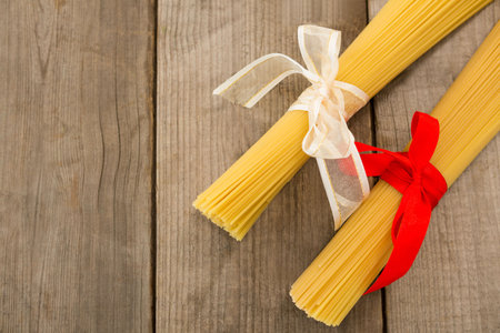 Overhead view of raw spaghetti tied with ribbons on wooden tableの写真素材