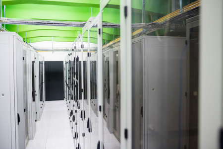 Server rack cabinets are lining aisle in flat design, featuring green beams and white floor tiles....