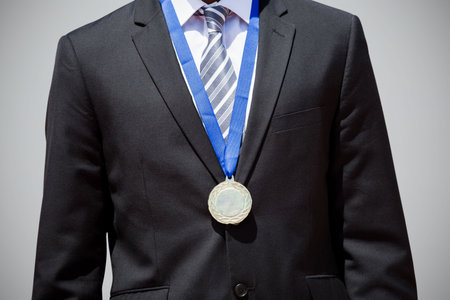 Midsection of businessman wearing medal against gray backgroundの写真素材