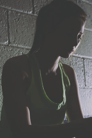 Disapponted female athlete sitting against stone wallの写真素材