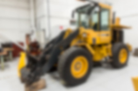 Defocused image of man inspecting earth mover parked at factory