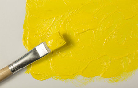 Yellow paint with paintbrush on white backgroundの写真素材