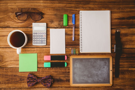 Flat-lay scene showing coffee cup, glasses, calculator, notepad, pen, highlighters on wood table....