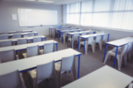 Desk and chairs arranged in classroomの写真素材
