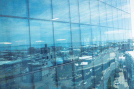 Defocussed image of modern cityscape and blue sky reflected in glass building, with copy space. Business, finance, growth and communication concept.の写真素材