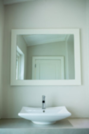 Defocused image of sink by mirror hanging on wall in bathroomの写真素材