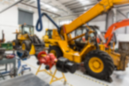 Yellow telescopic handler is standing in flat design maintenance workshop showing blue hoist hook....