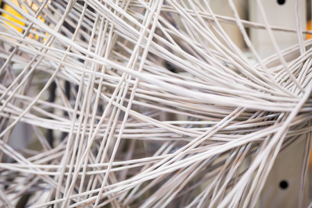Showing tangled white network cables crossing flat design rack patch panel with metal guides....