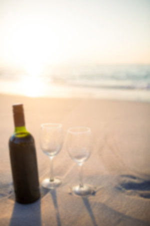 View of wine bottle and wineglasses on sandの写真素材