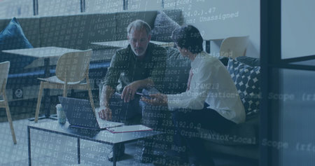 Two men in shirt and tie, green jacket coding on laptop in office lounge, with notebook. Collaboration, teamwork, innovation, modern, professional, lounge, technologyの写真素材