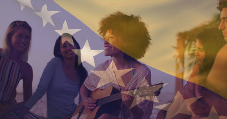 Strumming woman with curly hair playing acoustic guitar on sandy beach at sunset, striped blanket....