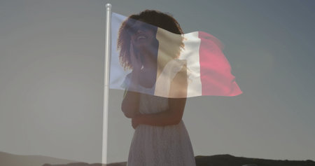 Standing woman in white lace dress gazing up at flagpole in landscape, with French flag waving. Solitude, patriotism, serenity, elegance, outdoor, minimalism, prideの写真素材