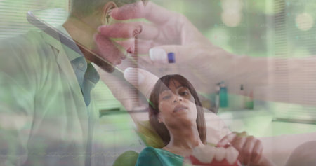 Leaning over patient dentist wearing white coat examining mouth in dental clinic, with dental mold. Professional, healthcare, medical, clinic, examination, dentistry, hygieneの写真素材