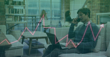 Man speaking on smartphone and typing on laptop in office lounge, with graph overlay, copy space. Collaboration, innovation, professional, modern, workspace, brainstorming, digitalの写真素材