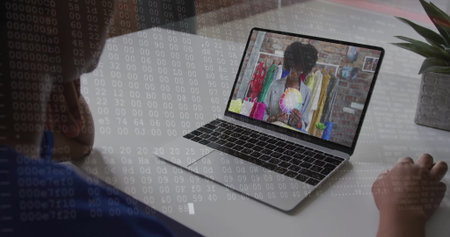 Watching person leaning on desk in home office, viewing silver laptop showing color wheel by rack....