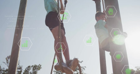 Climbing school-aged boys ascending wooden poles using thick ropes at park, with green data icons....