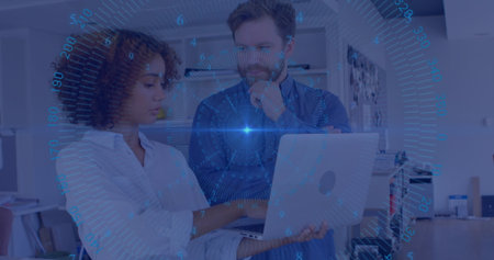 Two professionals analyzing data on laptop in modern office, with blue HUD overlay and shelving....