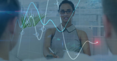 Writing Asian woman taking notes with pen at office conference table with holographic graph overlay....