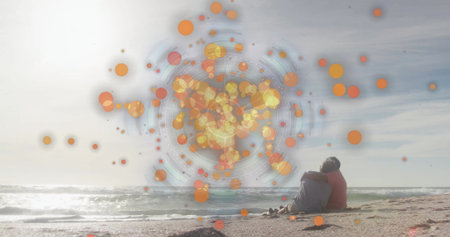 Sitting elderly couple in colorful jackets on ocean beach, with orange digital overlay, copy space. Seaside, companionship, relaxation, data visualization, tranquility, leisure, technologyの写真素材