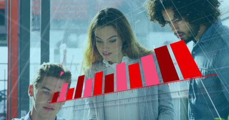Reviewing three professionals studying red bar chart projection in office space, with grid overlay. Business, teamwork, technology, innovation, collaboration, data, analyticsの写真素材