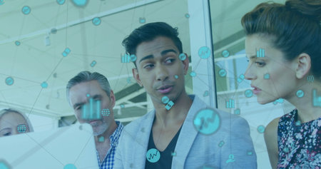 Presenting data on laptop in office by team with male wearing gray blazer, showing network icons....