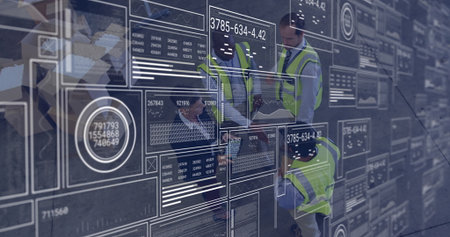 Analyzing digital data interfaces and graphs, engineers in safety vests working. Technology,...