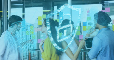 Collaborating team analyzing sticky notes on glass wall in office, with tablet and shield icon. Collaboration, innovation, brainstorming, technology, cybersecurity, workspace, digitalの写真素材