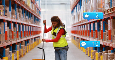 Warehouse worker wearing safety vest pushing pallet jack in warehouse aisle, with shelving racks....