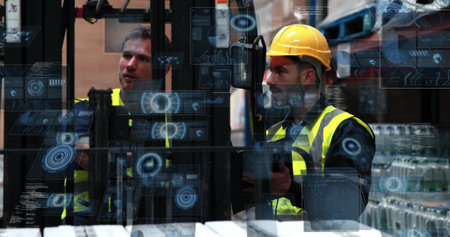 Two men wearing vests, helmet operating forklift controls in warehouse with shelving and pallets. Industrial, team, safety, logistics, storage, operational, modernの写真素材