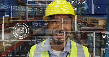 Mid adult man wearing yellow hard hat and vest monitoring inventory overlays in warehouse. Industrial, logistics, inventory, digital, organizational, safety, modernの写真素材
