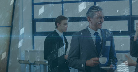 Holding cup and saucer, professional in suit speaking with colleague at coffee station, copy space....