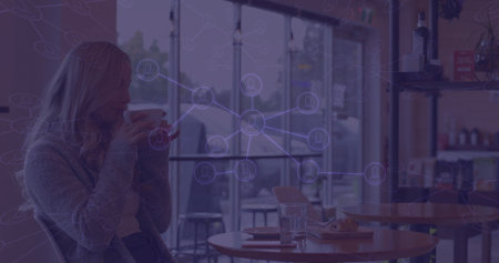 Sipping woman raising ceramic cup near mouth at cafÃ© window with network icons overlay, copy...