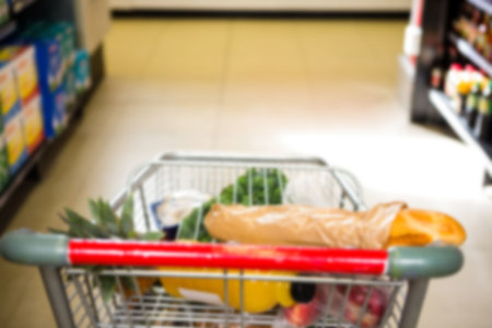 Food and bottle in shopping cart at supermarketの写真素材