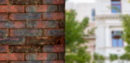Flat design showing weathered brick wall on left, with blurred building facade and green trees. Textures, urban, architecture, exterior, nature, vintage, structuralの写真素材