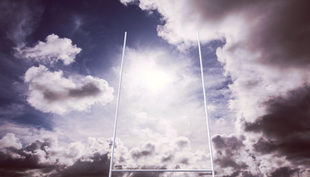 Rugby goalposts are standing under partly cloudy sky, with bright sunlight breaking through. Sports infrastructure, outdoor athletics, athletic field, athletic equipment, active lifestyle, stadium, competitive sportsの写真素材