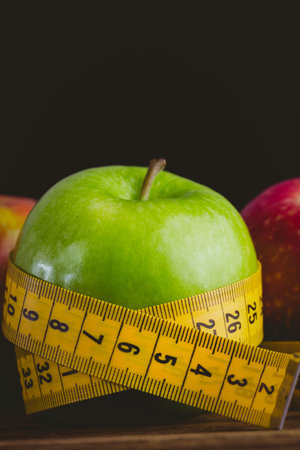 Red and green apples with measuring tape on wooden tableの写真素材