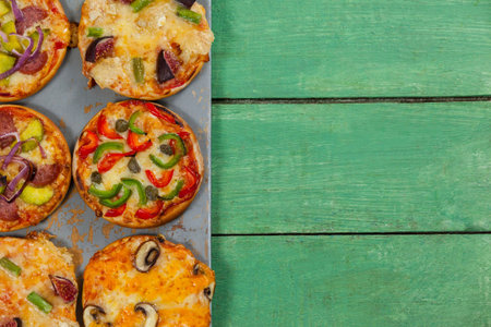 Overhead view of pizzas arranged on green wooden tableの写真素材